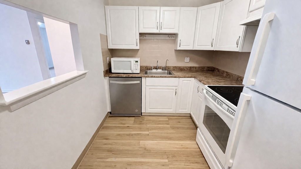 15 Weld Street, Unit 18 Framingham, MA 01702 - Photo 3 of 18 a kitchen with granite countertop white cabinets and white appliances