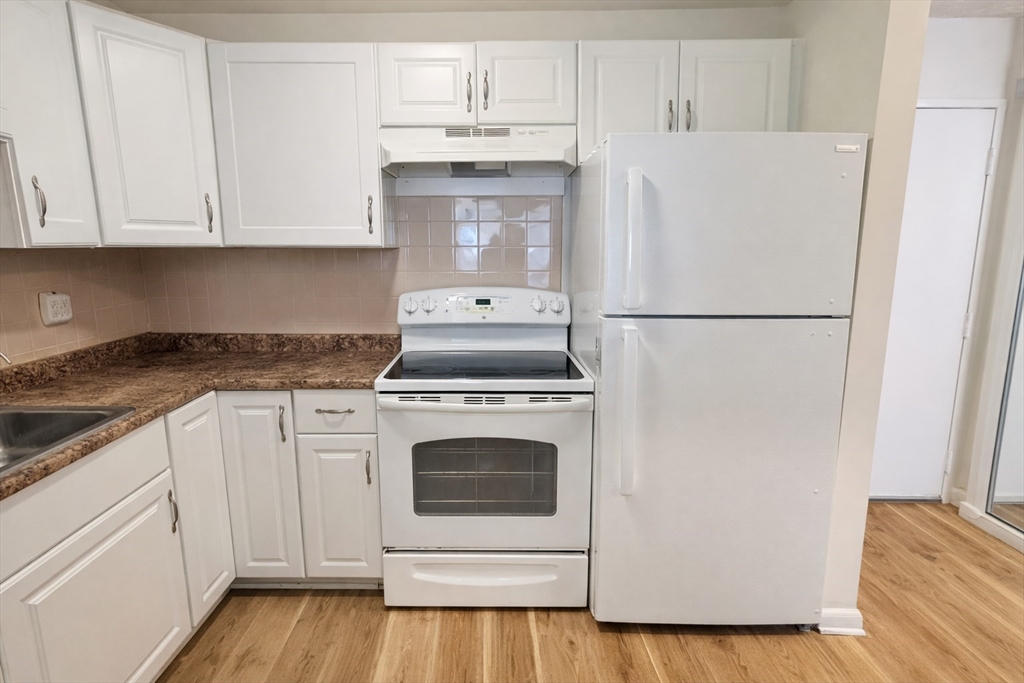 15 Weld Street, Unit 18 Framingham, MA 01702 - Photo 5 of 18 a white refrigerator freezer sitting inside of a kitchen with stainless steel appliances wooden floor