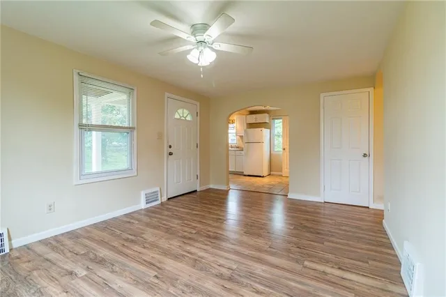 a view of an empty room with window and wooden floor