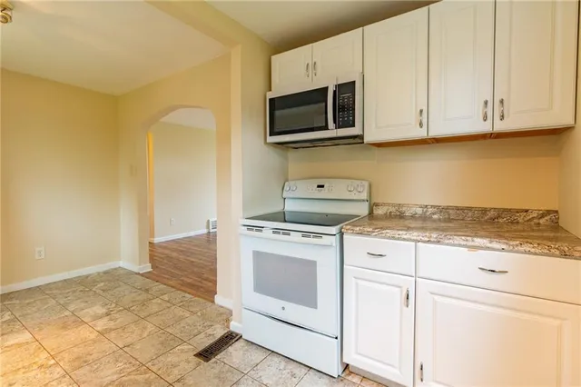a kitchen with granite countertop white cabinets and stainless steel appliances