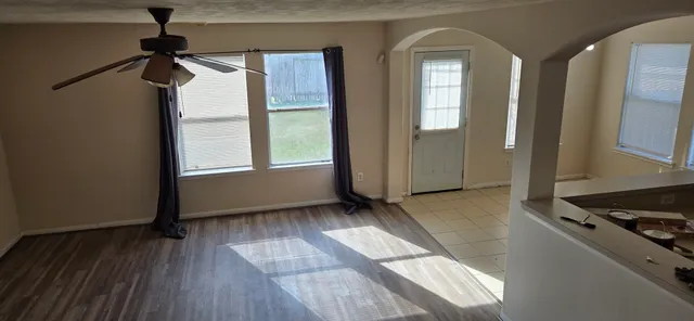 an empty room with wooden floor and windows