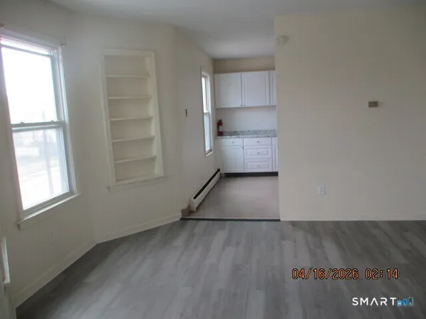 an empty room with wooden floor closet and windows
