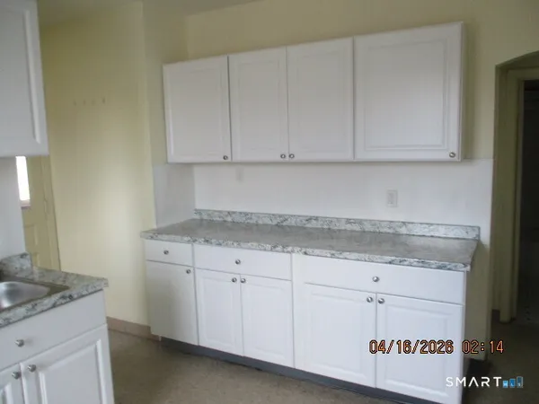 a kitchen with granite countertop white cabinets and a sink