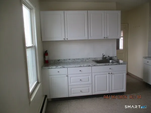 a kitchen with granite countertop white cabinets and sink