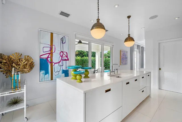 a large white kitchen with large windows and refrigerator