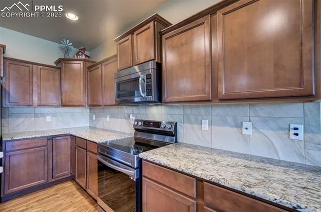 a kitchen with stainless steel appliances granite countertop a sink a stove and cabinets