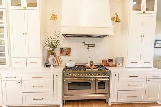 a kitchen with stainless steel appliances a stove and white cabinets