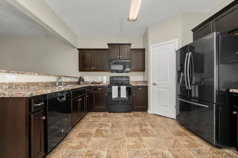 a large kitchen with a stove top oven a refrigerator and a sink