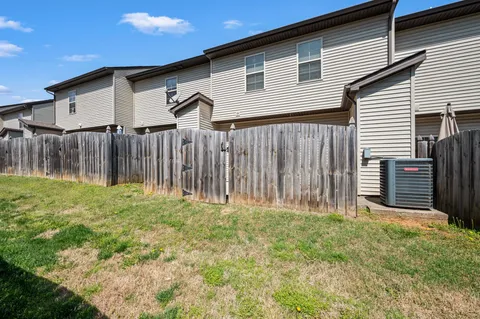 a backyard of a house with grass and wooden fence
