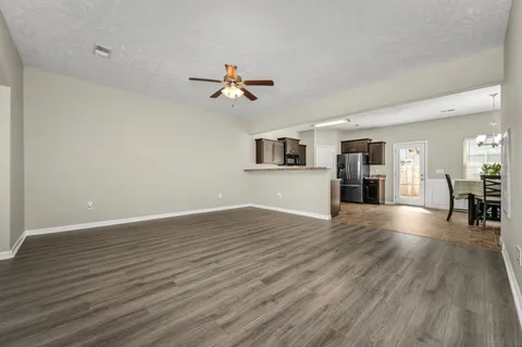 a view of empty room with wooden floor and ceiling fan