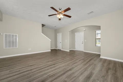 an empty room with wooden floor and ceiling fan