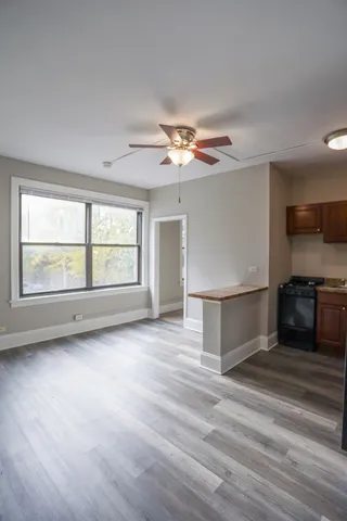 an empty room with wooden floor ceiling fan and windows