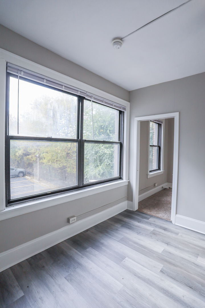5326 South Cornell Avenue, Unit 207 Chicago, IL 60615 - Photo 6 of 12 a view of an empty room with a window and wooden floor