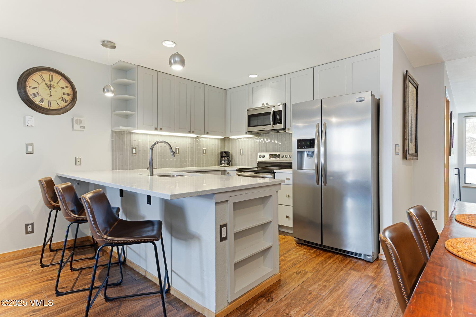 1100 North Frontage Road West, Unit 2311 Vail, CO 81657 - Photo 10 of 34 a kitchen with stainless steel appliances granite countertop a dining table chairs refrigerator and cabinets