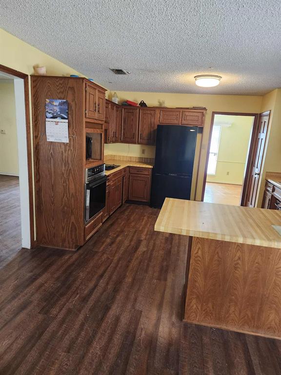 1316 Edna Street Commerce, TX 75428 - Photo 7 of 16 a kitchen with stainless steel appliances wooden cabinets a refrigerator and a stove