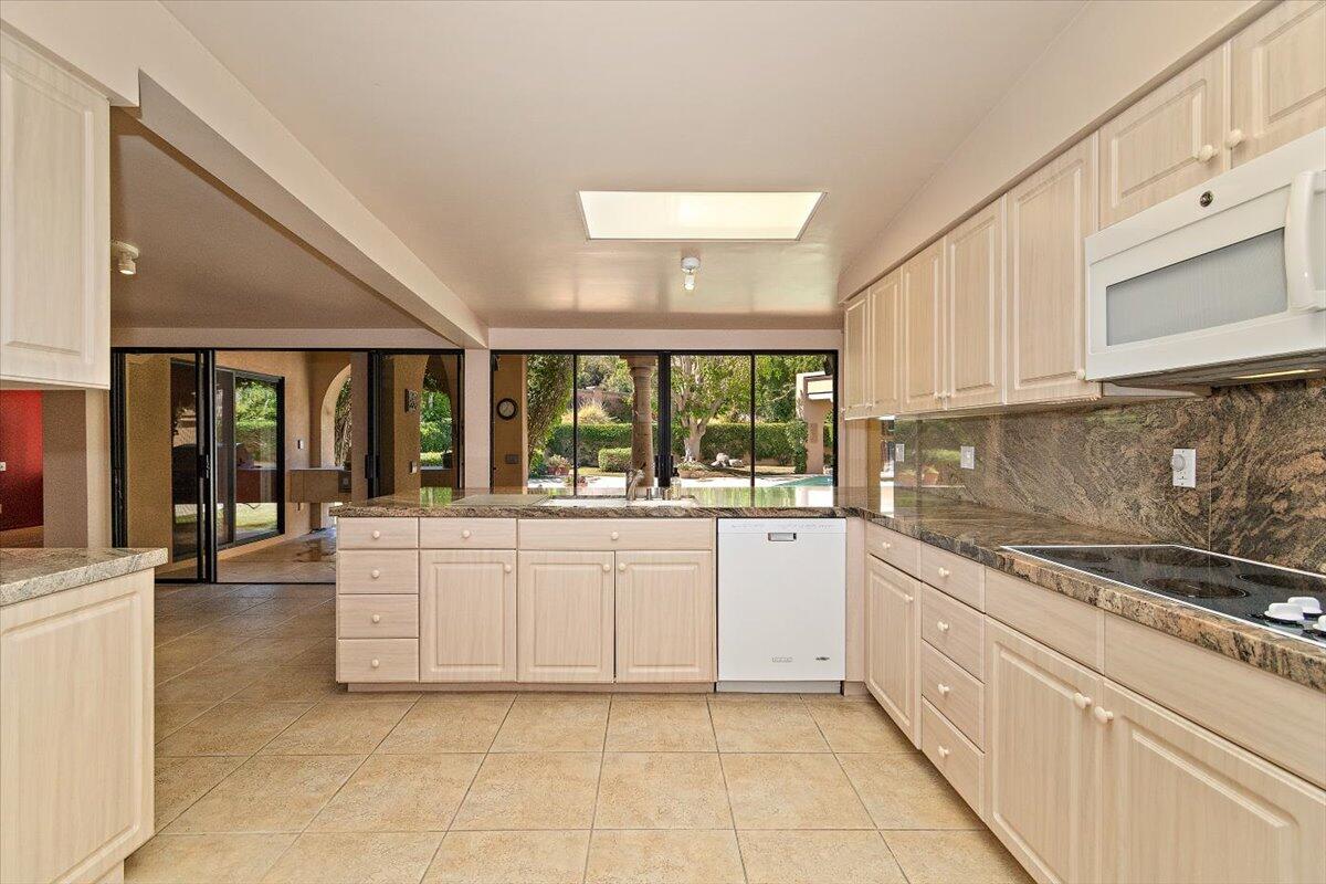 40885 Thunderbird Road Rancho Mirage, CA 92270 - Photo 19 of 61 a large white kitchen with granite countertop a stove top oven a sink with dishwasher and cabinets