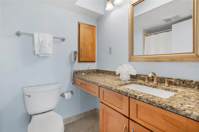 a bathroom with a granite countertop toilet sink and mirror
