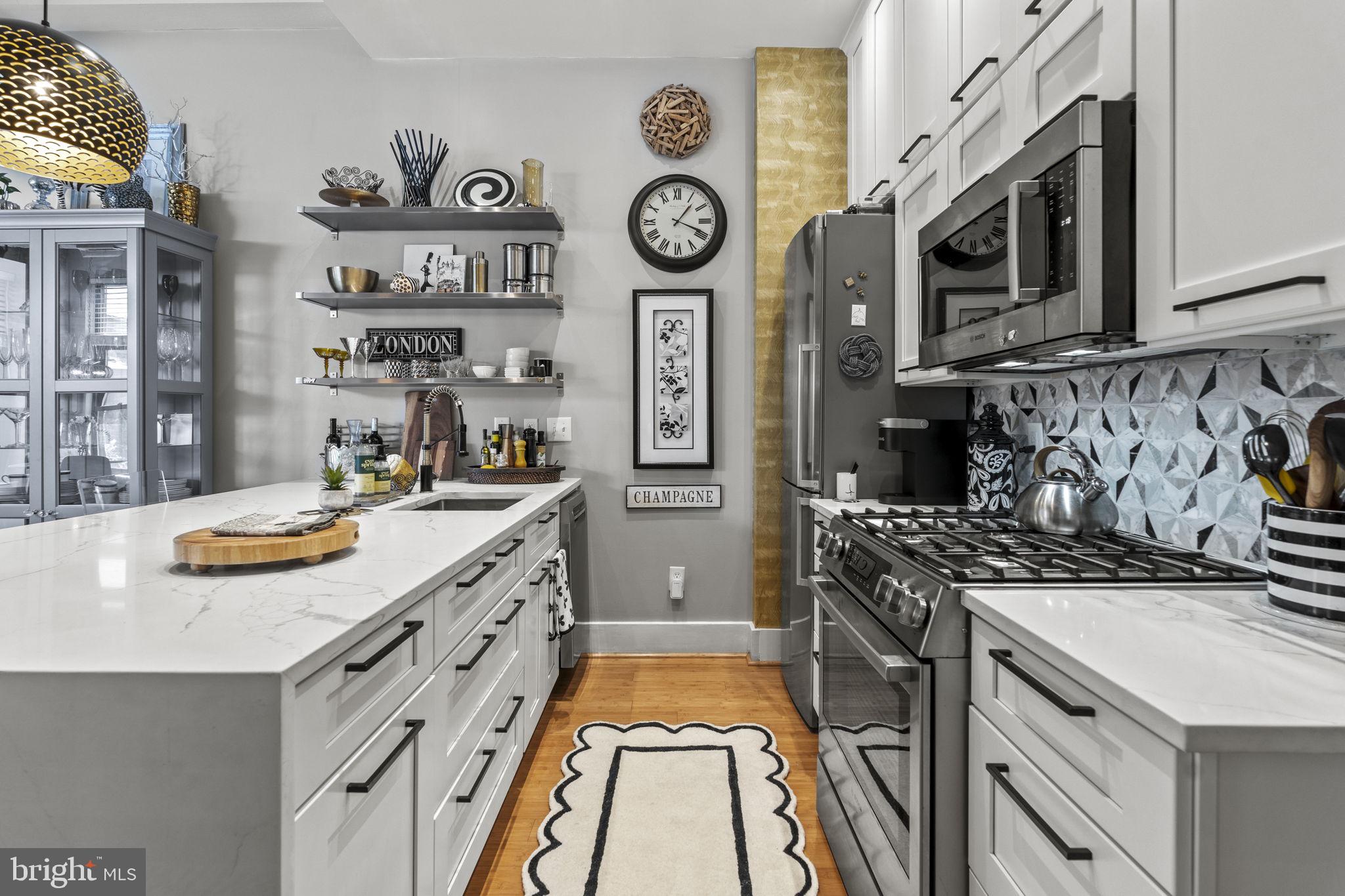 a kitchen with stainless steel appliances granite countertop a stove and a clock on the wall