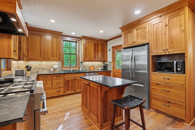 a kitchen with granite countertop a refrigerator stove top oven and sink