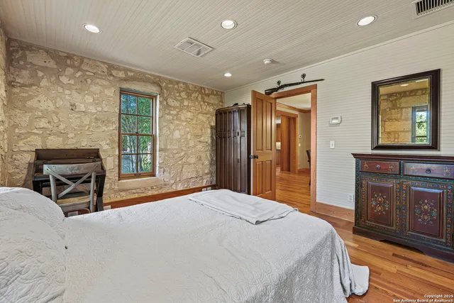 a spacious bedroom with a bed a dresser and wooden floor