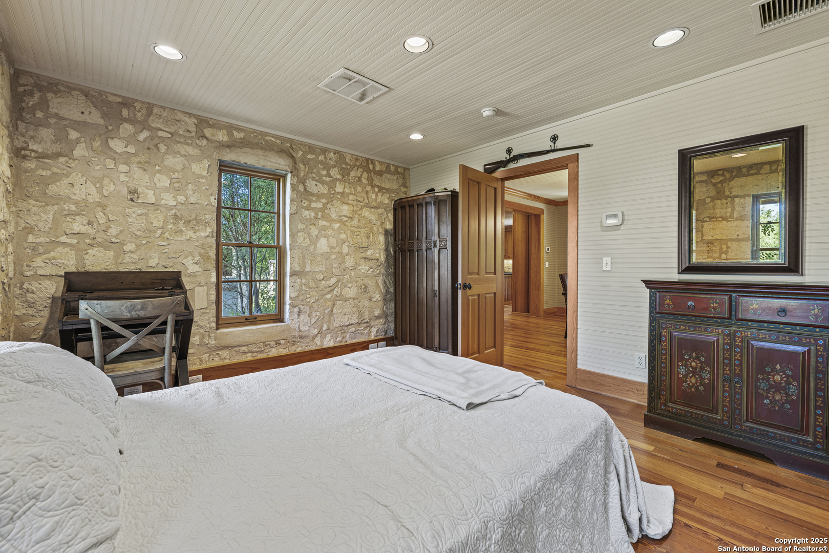 9402 Doss-Spring Creek Road Doss, TX 78618 - Photo 8 of 42 a spacious bedroom with a bed a dresser and wooden floor
