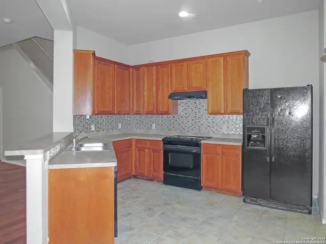 a kitchen with stainless steel appliances granite countertop a sink and a refrigerator