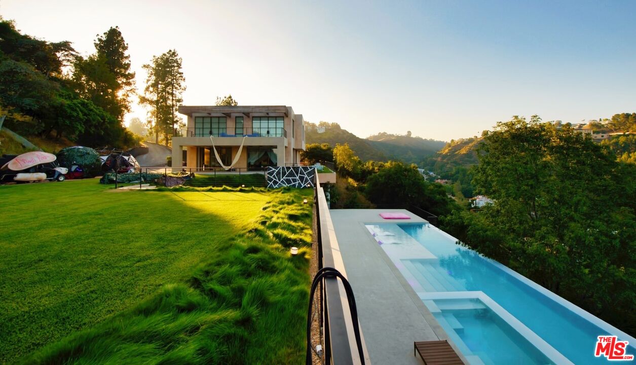 11531 Orum Road Los Angeles, CA 90049 - Photo 24 of 27 a view of a swimming pool with lawn chairs and large trees