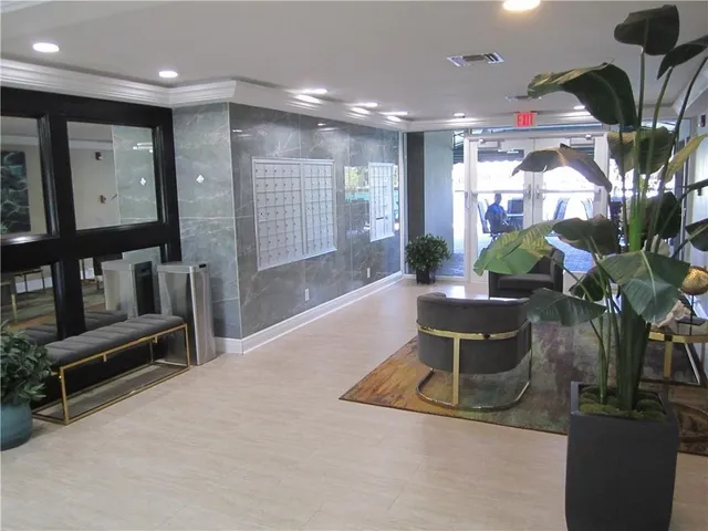 a living room with furniture a potted plant and a kitchen view