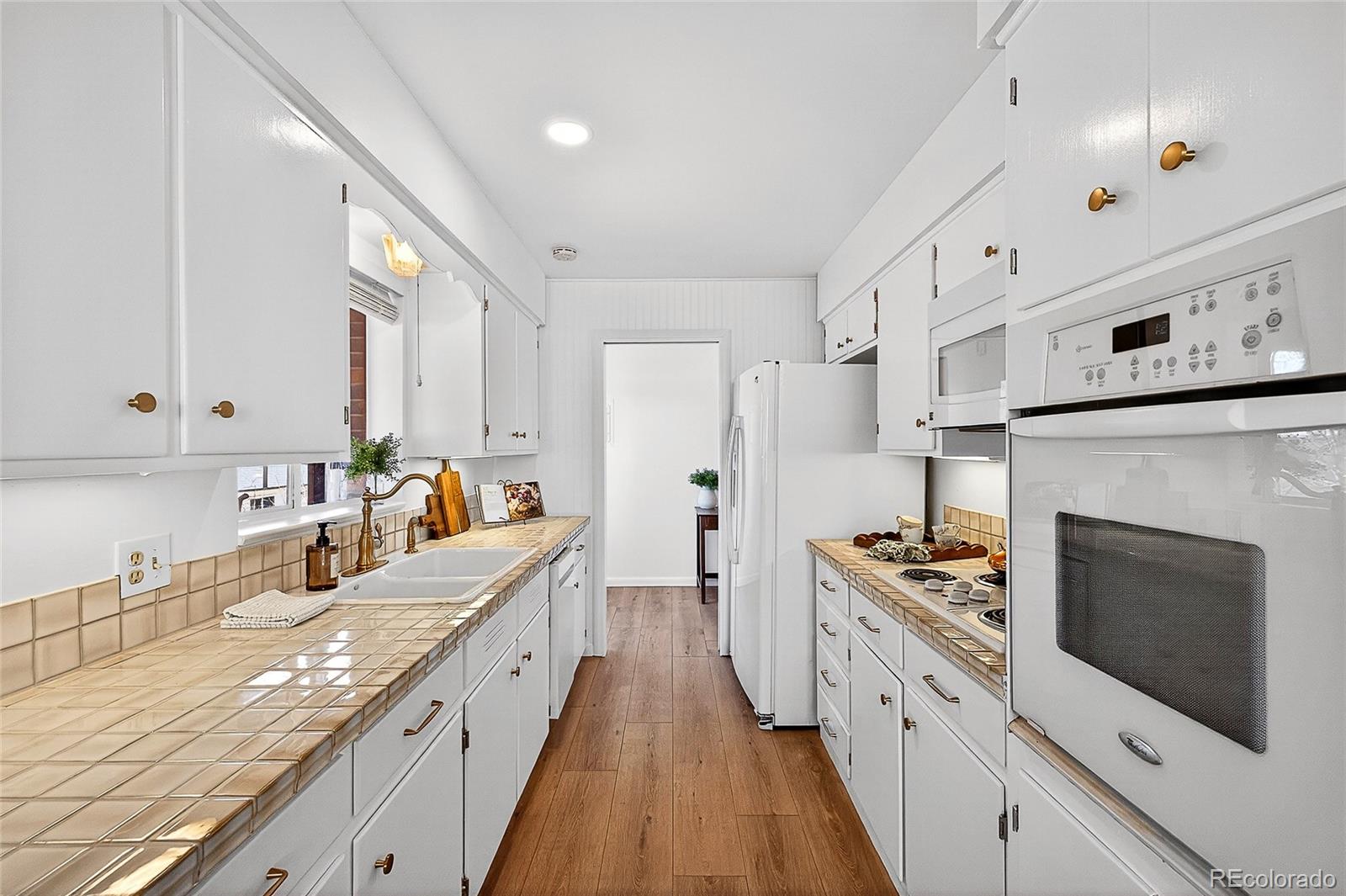 2768 South Mabry Way Denver, CO 80236 - Photo 11 of 39 a large kitchen with stainless steel appliances kitchen island granite countertop a stove a sink dishwasher and a refrigerator with wooden floor
