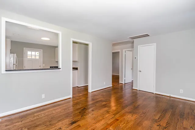 an empty room with wooden floor and mirror