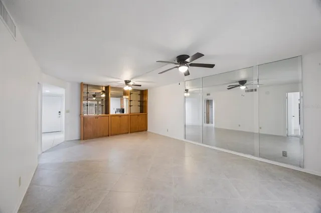 an empty room with chandelier fan and windows
