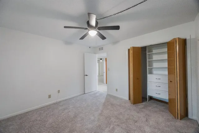 an empty room with closet and a ceiling fan