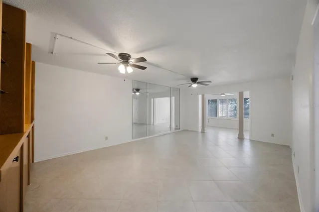 an empty room with ceiling fan and window