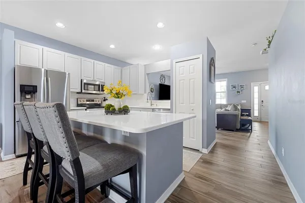 a kitchen with stainless steel appliances a sink a stove a refrigerator cabinets and wooden floor