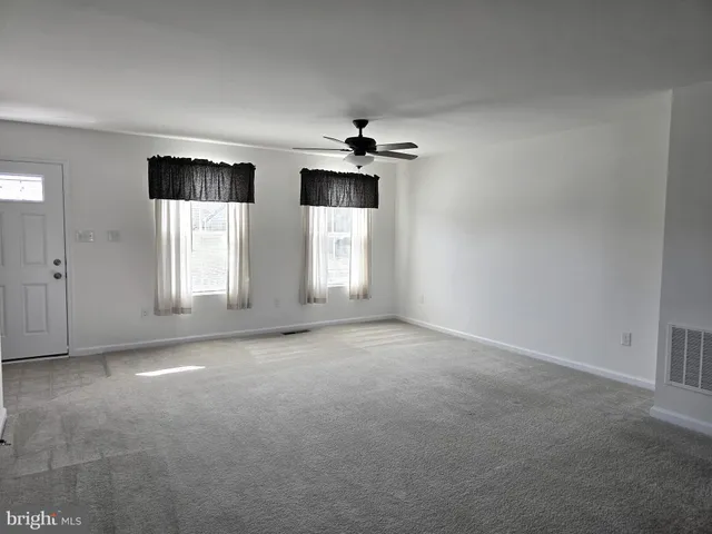 an empty room with windows and ceiling fan