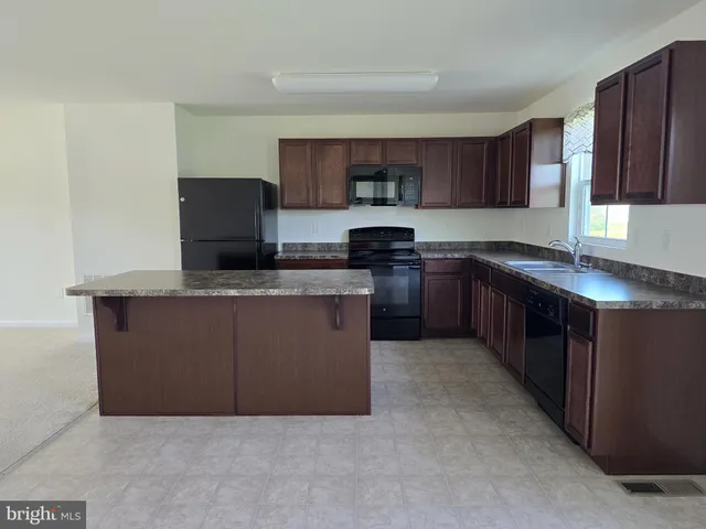 a kitchen with stainless steel appliances granite countertop a stove a sink a microwave a refrigerator and cabinets