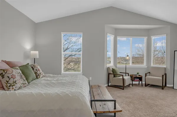 a spacious bedroom with a bed a table and large window