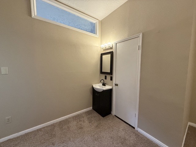 1809 Whitney Way Austin, TX 78741 - Photo 13 of 25 Primary bedroom ensuite with a spacious vanity with storage, porcelain sink, modern mirror and light fixture.