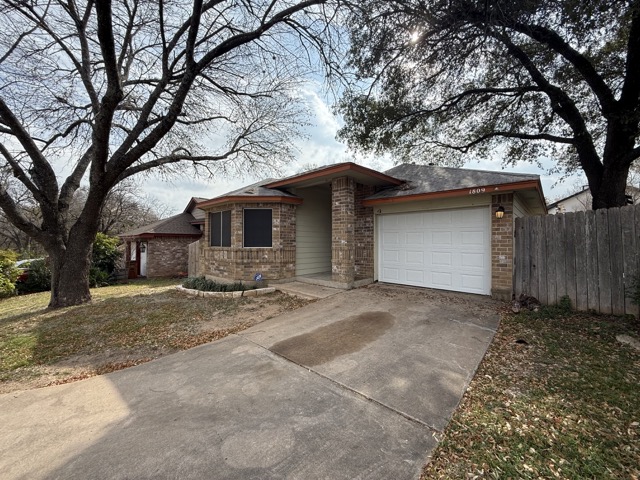 1809 Whitney Way Austin, TX 78741 - Photo 23 of 25 View of front of property with brick siding, driveway, and a one-car garage.