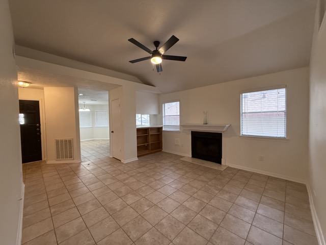 1809 Whitney Way Austin, TX 78741 - Photo 25 of 25 Unfurnished living room with a fireplace with flush hearth, ceiling fan, light tile patterned floors, and vaulted ceiling