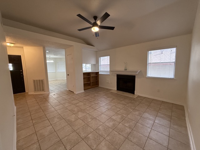 1809 Whitney Way Austin, TX 78741 - Photo 3 of 25 Spacious and bright living room with a fireplace with flush hearth, a ceiling fan, light tile patterned flooring, and vaulted ceiling.