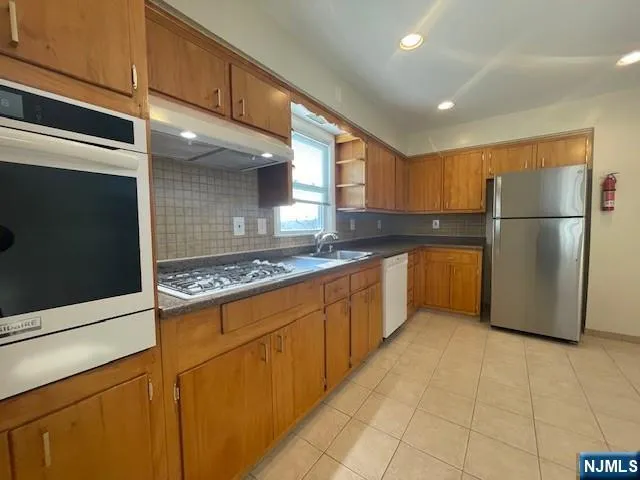 a kitchen with stainless steel appliances granite countertop a refrigerator a stove and a sink