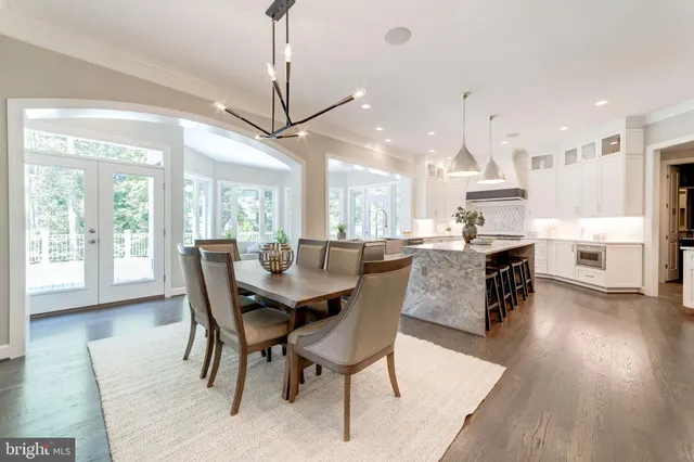 a dining room with stainless steel appliances kitchen island granite countertop a table chairs and a living room
