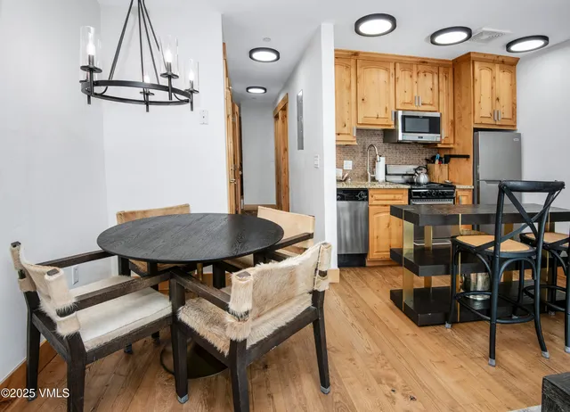 a kitchen with stainless steel appliances a table chairs in it and wooden floors