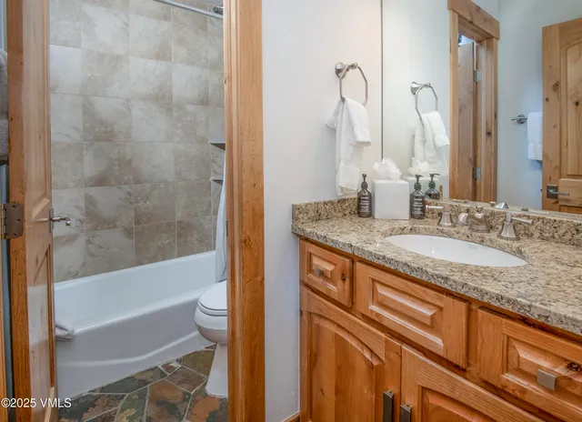 a bathroom with a granite countertop sink toilet and bathtub
