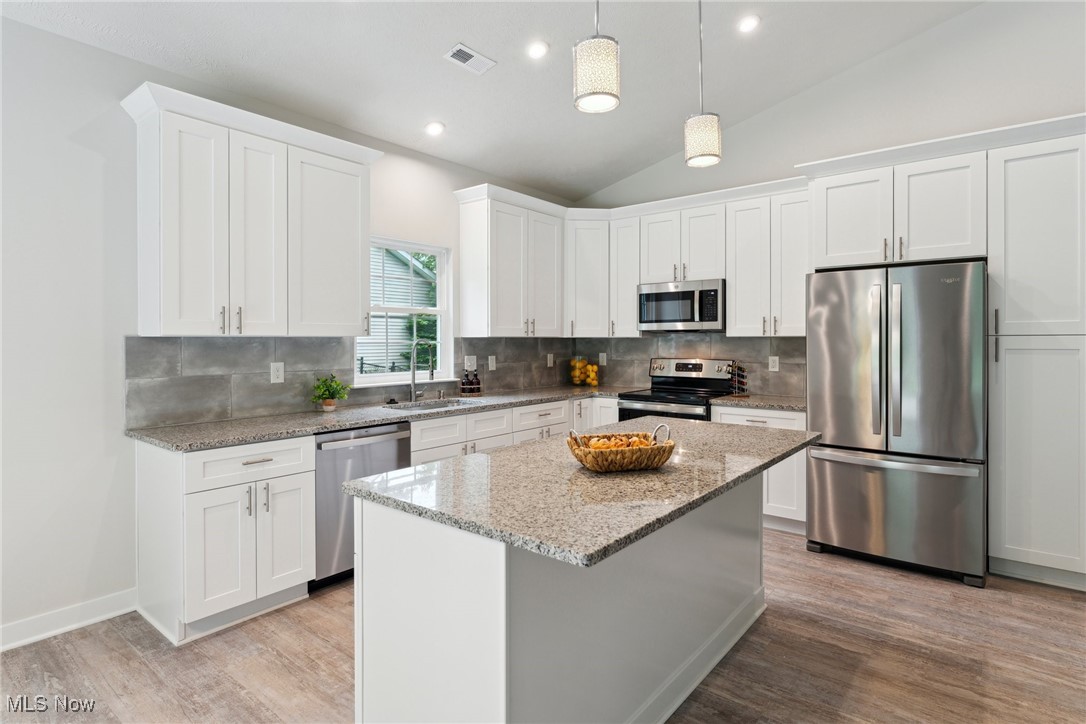 7605 Lake Road East Madison, OH 44057 - Photo 11 of 50 Kitchen with appliances with stainless steel finishes, light wood-style flooring, a sink, decorative backsplash, and lofted ceiling