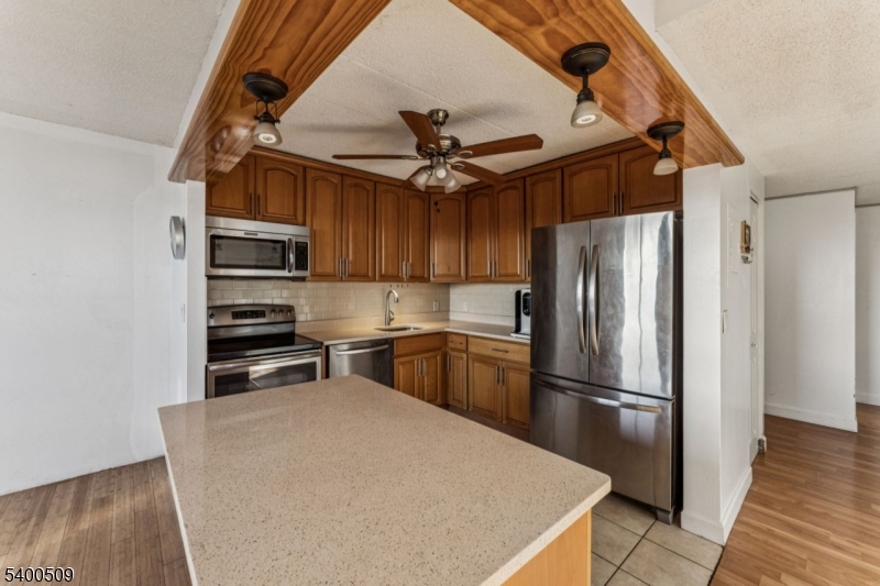 170 Lafayette Avenue, Unit 11E Passaic, NJ 07055 - Photo 13 of 32 a kitchen with stainless steel appliances a refrigerator a stove a sink and a dining table with wooden floor