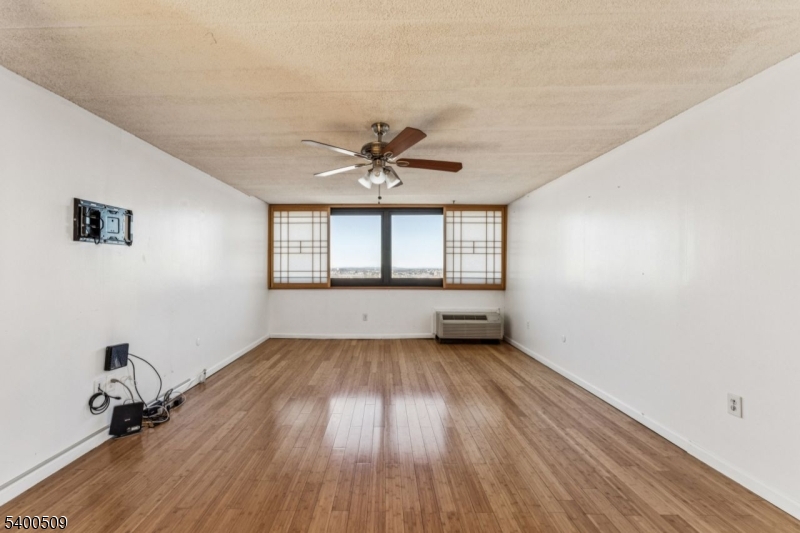 170 Lafayette Avenue, Unit 11E Passaic, NJ 07055 - Photo 5 of 32 an empty room with wooden floor and windows