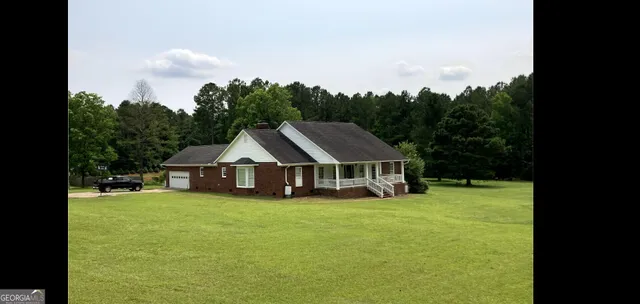 a white house with a big yard and large trees