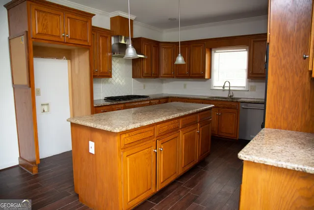 a kitchen with stainless steel appliances granite countertop a refrigerator a sink dishwasher a stove and a dining table with wooden floor